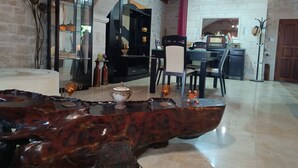 A spacious room with a wooden coffee table, a dining area with chairs, and a kitchen in the background.