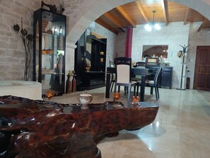 A spacious room with a wooden coffee table, a dining area with chairs, and a kitchen in the background.