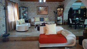 A cozy living room with a stone wall, a wooden ceiling, and a red sofa.