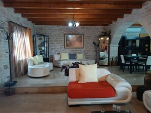 A cozy living room with a stone wall, a wooden ceiling, and a red sofa.