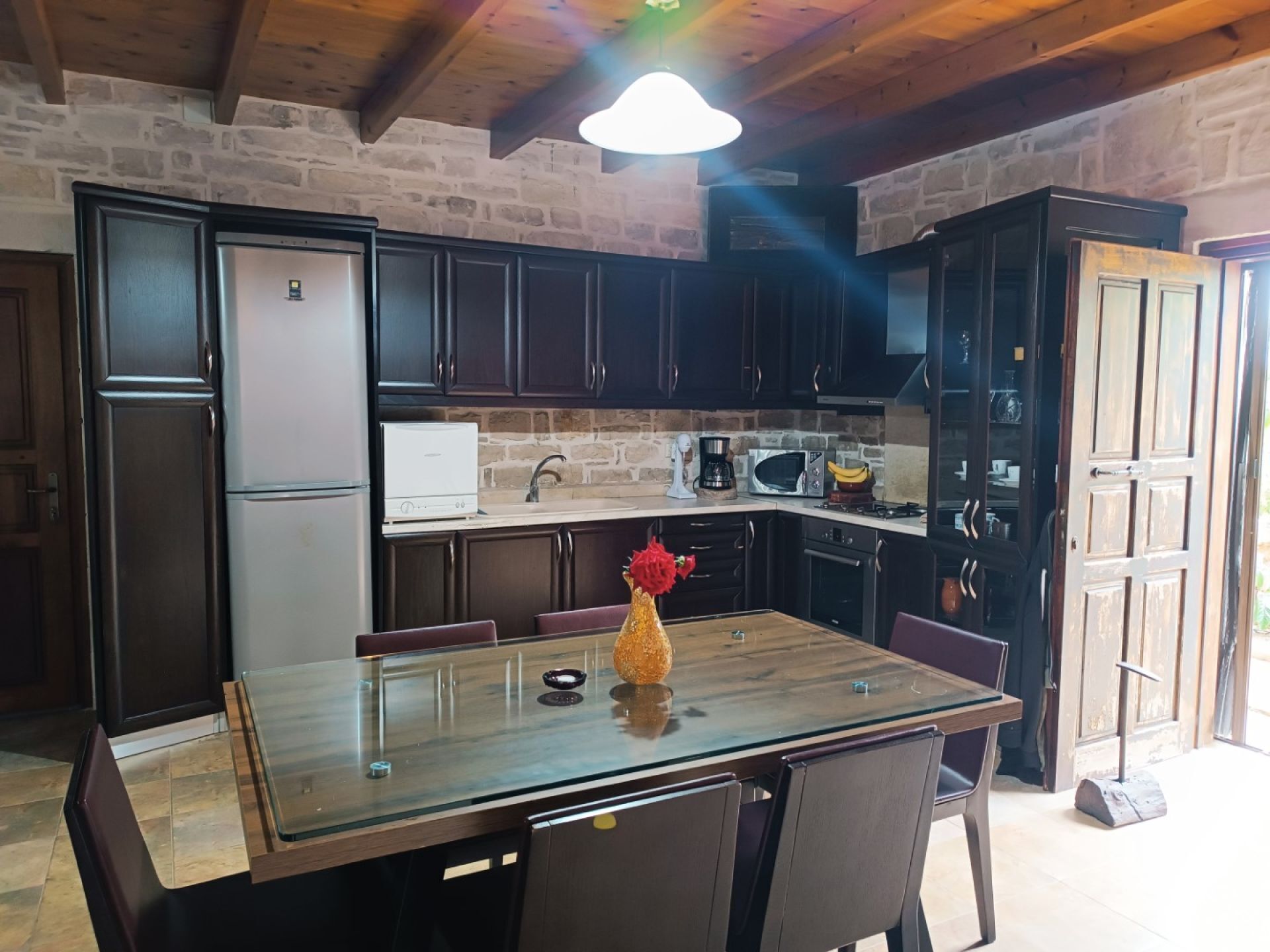 A kitchen with dark wooden cabinets, a stainless steel refrigerator, a microwave, and a coffee maker.