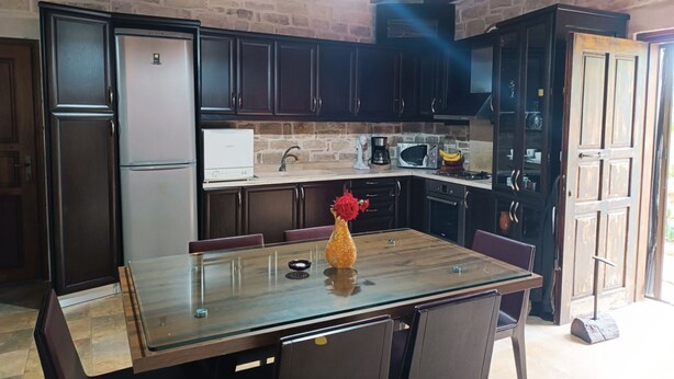 A kitchen with dark wooden cabinets, a stainless steel refrigerator, a microwave, and a coffee maker.