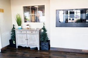 Un área de recepción con un mueble de madera, una planta en maceta y un pequeño árbol de Navidad.