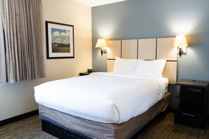 Une chambre d’hôtel avec un grand lit, deux lampes de chevet, une table de nuit et un tableau encadré au mur.