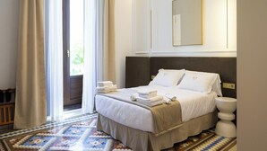 Une chambre d’hôtel avec un lit, une table de chevet, un miroir et un sol à motifs.