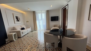 Un salon moderne avec un sol à motifs, un canapé, une table basse et un téléviseur fixé au mur.