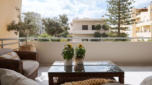 A balcony with wicker furniture, a glass table, and potted plants. - Voula Calm Living | Igias 5-7 | Voula 166 73, Bill & John Villas (Vari - Voula - Vouliagmeni)