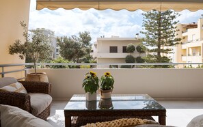 A balcony with wicker furniture, a glass table, and potted plants. - Voula Calm Living | Igias 5-7 | Voula 166 73, Bill & John Villas (Vari - Voula - Vouliagmeni)