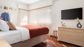 A bedroom with a bed, a dresser, a TV, and a window with curtains. - Voula Calm Living | Igias 5-7 | Voula 166 73, Bill & John Villas (Vari - Voula - Vouliagmeni)