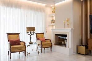 A living room with two armchairs, a fireplace, and a television. - Voula Calm Living | Igias 5-7 | Voula 166 73, Bill & John Villas (Vari - Voula - Vouliagmeni)