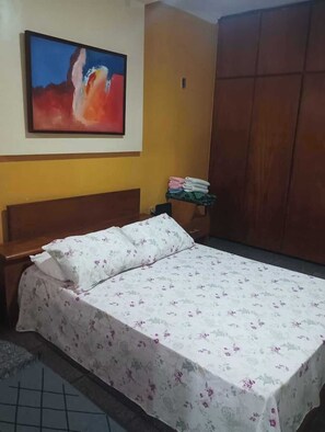 Ein Schlafzimmer mit einem Bett, einem Nachttisch, einem Bild an der Wand und einem Kleiderschrank.