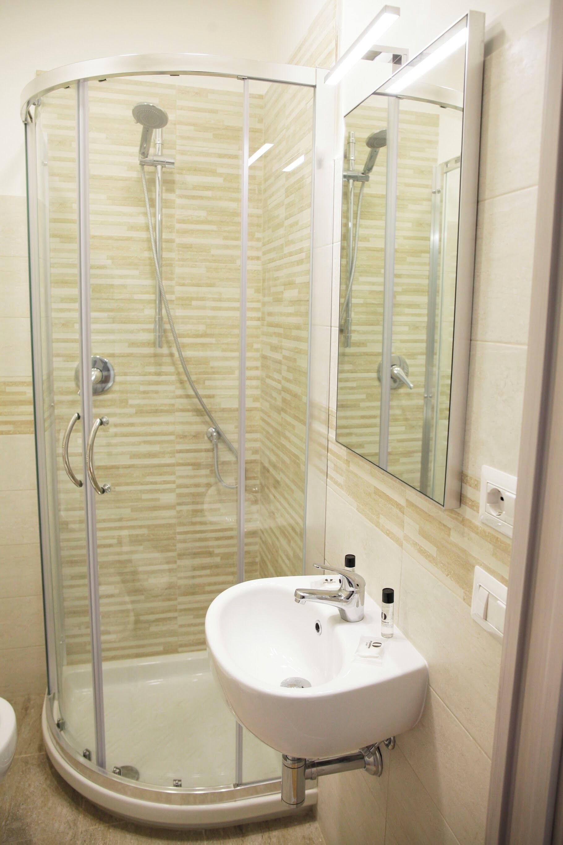 Une salle de bain moderne avec une douche à parois de verre, un lavabo blanc et un miroir.