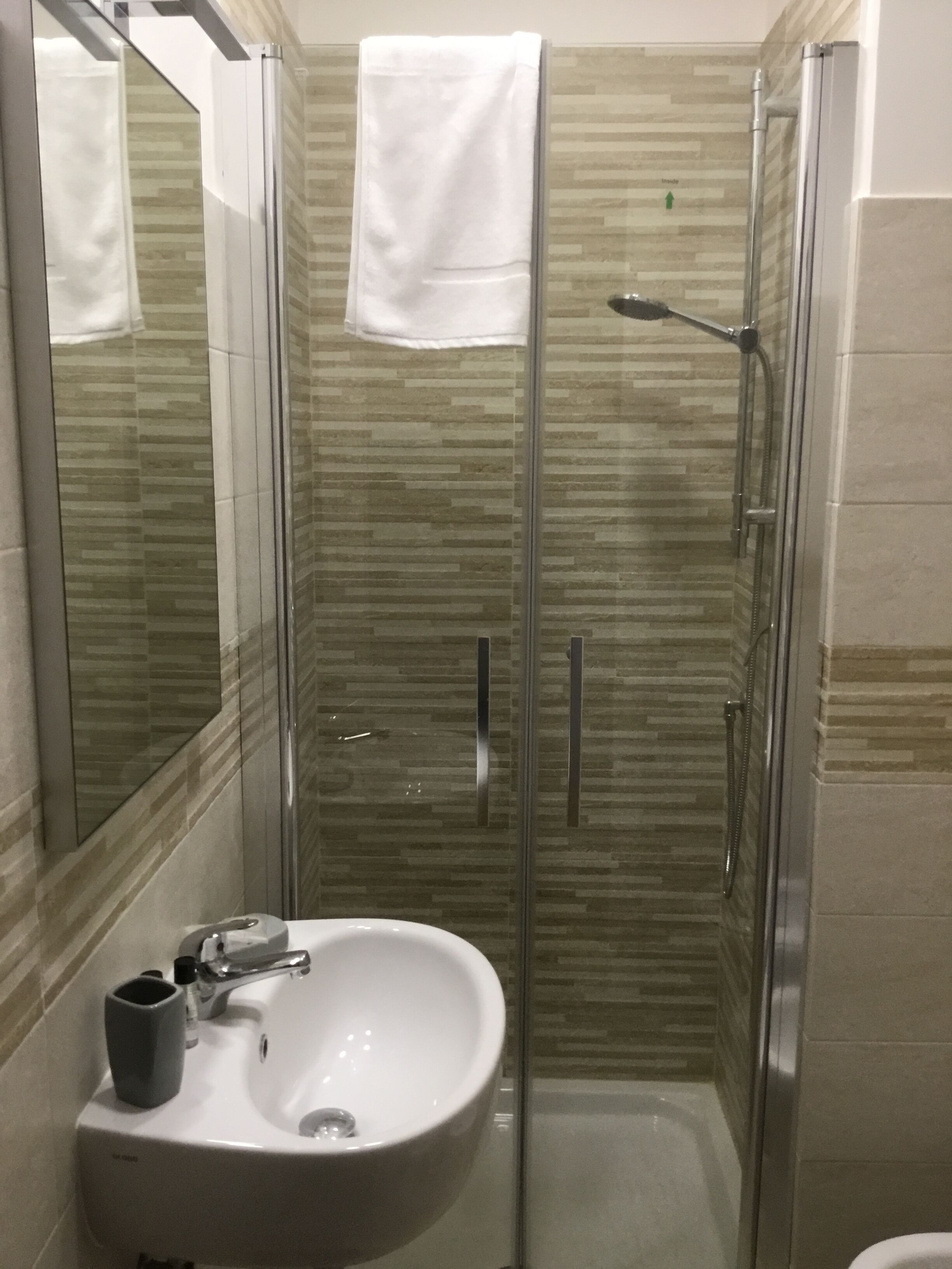Een badkamer met een douchecabine van glas, een wit wastafelmeubel en een spiegel.