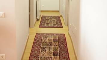 A narrow hallway with two doors on either side, a radiator on the left, and a patterned rug on the floor.