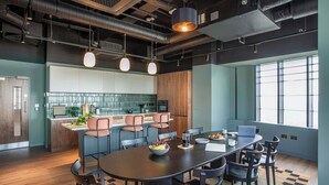 Een moderne keuken met een centraal eiland, een bar met zitplaatsen en een eethoek met een grote tafel en stoelen.