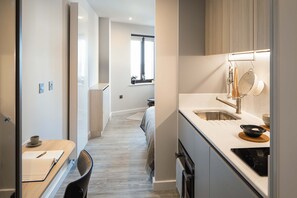 A modern kitchen with a built-in oven, a sink, and a window. - Central Croydon Studio | 40+ Amenities | StayCozy (Croydon)