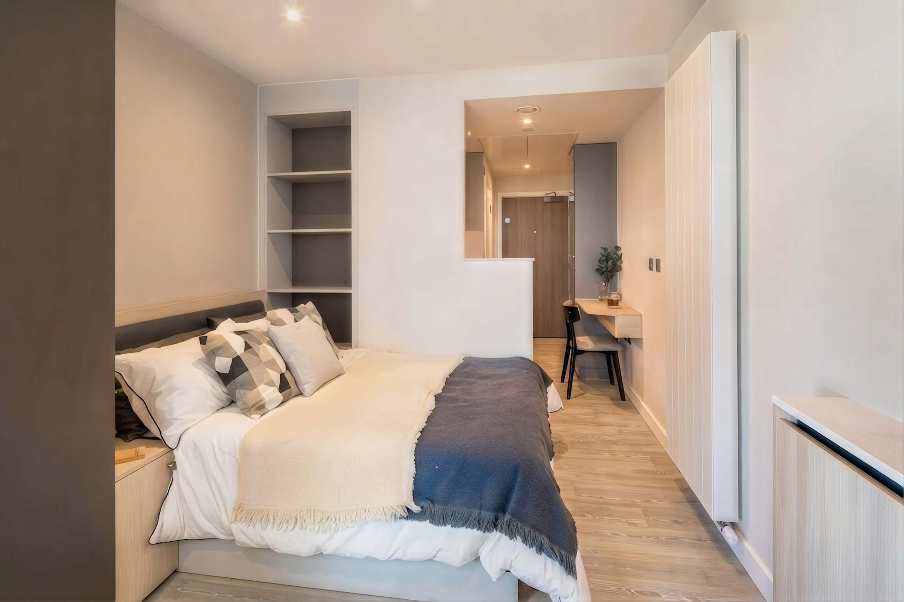 A modern bedroom with a bed, bedside tables, a desk, and a chair.