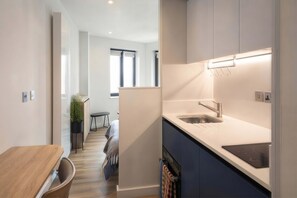 A modern kitchen with a built-in dishwasher, a sink, and a countertop. - Central Croydon Studio | 40+ Amenities | StayCozy (Croydon)