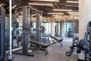 Une salle de sport équipée de matériel de musculation, de bancs et d’haltères.
