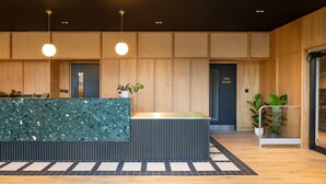 A modern reception desk with a green marble top, wooden panel walls, and a sign indicating a mail room. - Central Croydon Studio | 40+ Amenities | StayCozy (Croydon)