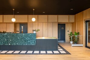 A modern reception desk with a green marble top, wooden panel walls, and a sign indicating a mail room. - Central Croydon Studio | 40+ Amenities | StayCozy (Croydon)