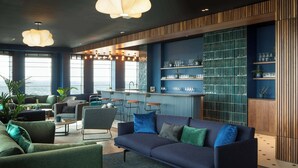 A modern lounge area with a sofa, armchairs, and a bar with stools. - Central Croydon Studio | 40+ Amenities | StayCozy (Croydon)