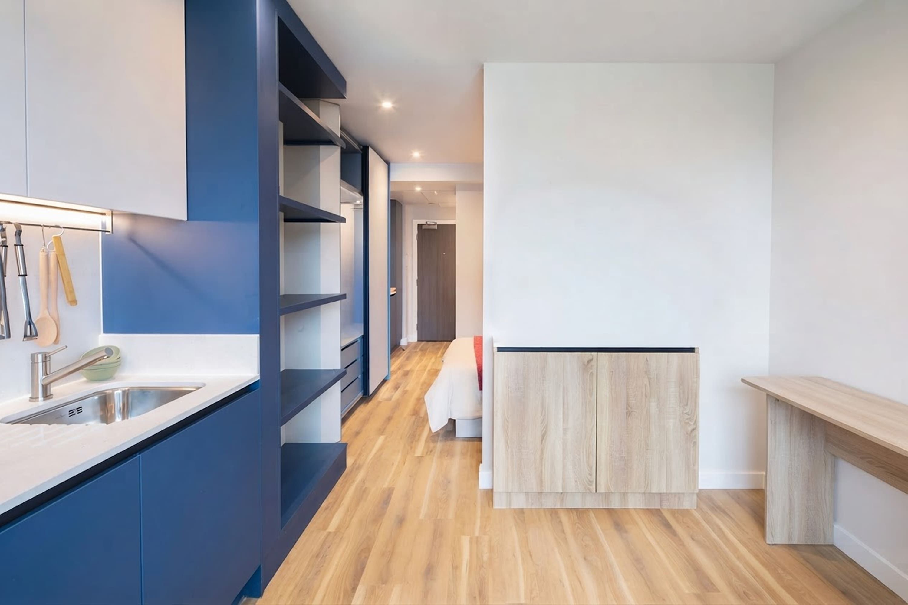 Une cuisine moderne dotée d’un évier encastré, de planchers en bois et d’un mur d’accent bleu.