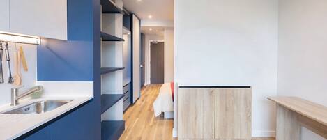 Une cuisine moderne dotée d’un évier encastré, de planchers en bois et d’un mur d’accent bleu.