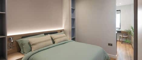 Un dormitorio moderno con cama, mesitas de noche, una estantería empotrada y un espejo.