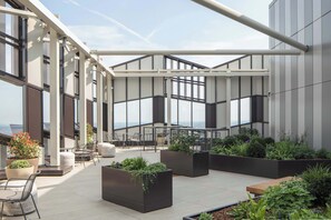 A rooftop terrace with outdoor seating, planters with greenery, and large windows offering views. - Comfy Digital Nomad Studio | Gym Access | StayCozy (Croydon)