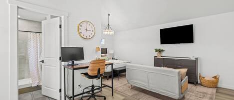 Una habitación de hotel moderna con escritorio, silla, cama, televisor y un reloj en la pared.