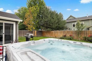 A backyard with a hot tub, a barbecue grill, and a wooden fence. - The High Roller House | Hot Tub & Pool Table (Meridian)