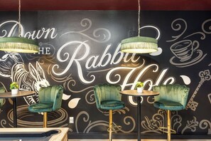 A restaurant interior with green upholstered chairs, round tables, and a wall with a rabbit-themed mural. - The High Roller House | Hot Tub & Pool Table (Meridian)