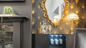 A bar area with a mirror, a bottle of liquor, and glasses on a shelf. - The High Roller House | Hot Tub & Pool Table (Meridian)
