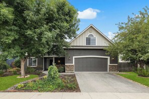 A residential house with a garage, a driveway, and a well-maintained lawn. - The High Roller House | Hot Tub & Pool Table (Meridian)