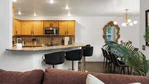A modern kitchen with wooden cabinets, a built-in microwave, and a granite countertop. - The High Roller House | Hot Tub & Pool Table (Meridian)