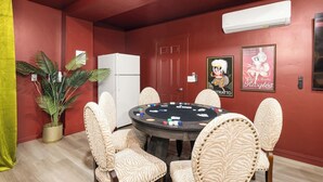 A room with a poker table, chairs, a refrigerator, and wall decorations. - The High Roller House | Hot Tub & Pool Table (Meridian)