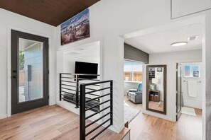 A modern interior with a staircase, a flat-screen TV mounted on a wall, and a door leading to another room. - Central Boise Getaway, Walkable, Firepit, Grill, Newly Remodeled (Boise)