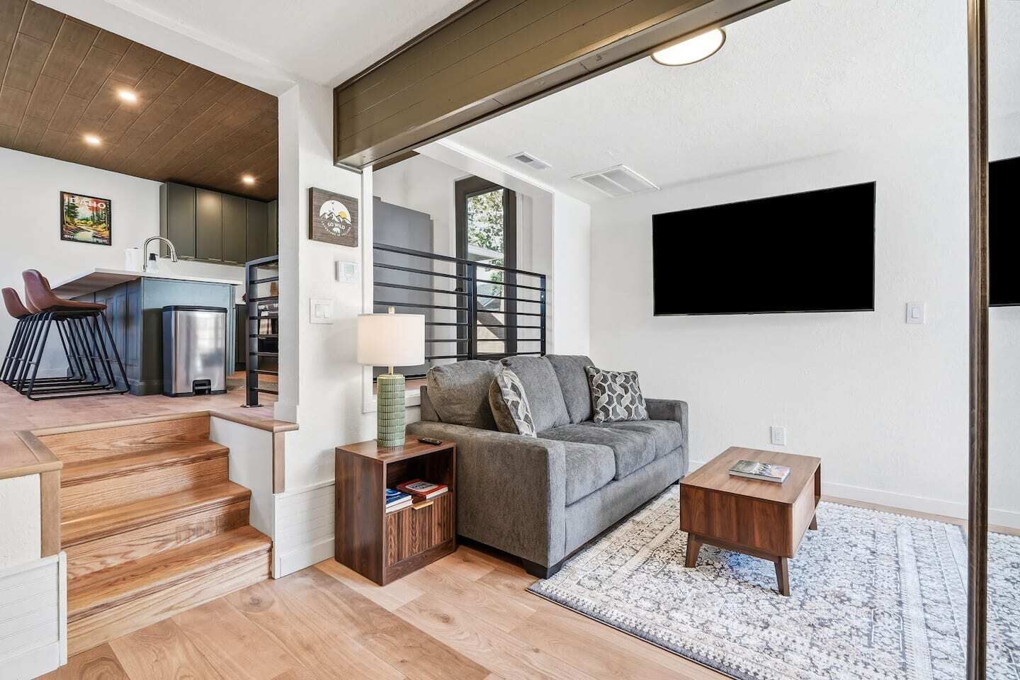 A modern living room with a grey sofa, a coffee table, and a TV mounted on the wall.