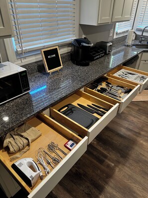 Una cocina equipada con microondas, cafetera y un organizador de cajones con utensilios.