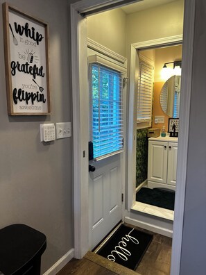 Ein Flur mit einer zur Toilette führenden Tür, einer Wandleuchte und einer Fußmatte mit dem Schriftzug 'Molly'.