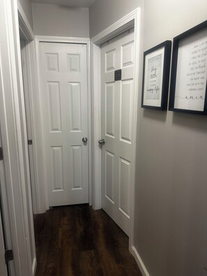 Un pasillo con dos puertas blancas, piso de madera y citas inspiradoras enmarcadas en la pared.