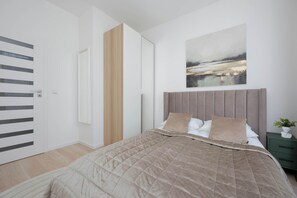 Ein modernes Schlafzimmer mit einem Bett, einem Bild, einem grünen Nachttisch und einer Tür mit einer vertikalen Holzverkleidung.