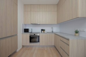 Uma cozinha compacta com armários de madeira, forno embutido, micro-ondas e pia.