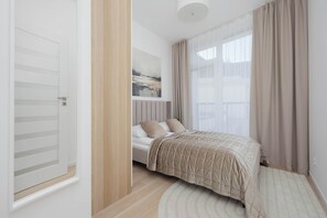 A bedroom with a bed, a painting on the wall, and a window with curtains. - Stylish Apartment with a Balcony | View of the Skyscrapers (Warszawa)