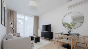En moderne stue med sofa, sofabord, fjernsyn og spiseplads med stole og bord.
