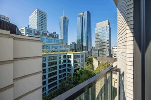A modern urban skyline with high-rise buildings, including a distinctive curved skyscraper and a building with a unique angular design. - Stylish Apartment with a Balcony | View of the Skyscrapers (Warszawa)