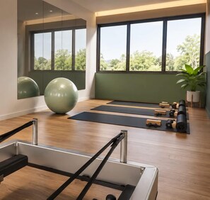 A yoga studio with wooden flooring, exercise balls, yoga mats, and a Pilates reformer.