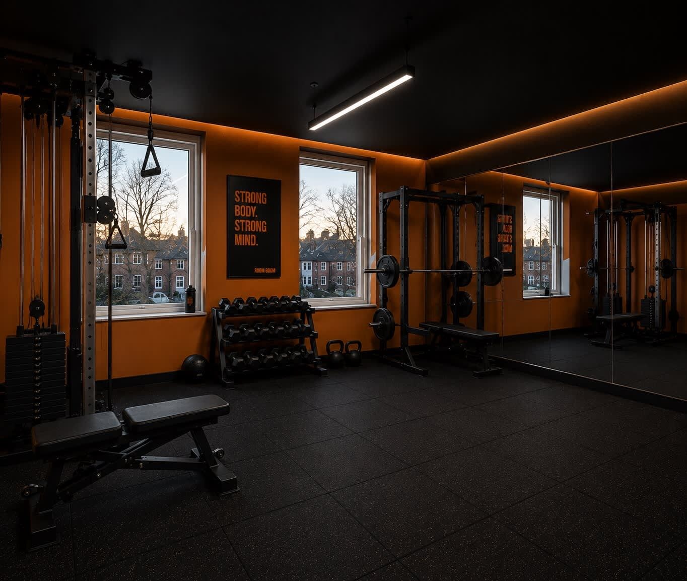 Ett gym med utrustning för styrketräning, en bänk och en motivationsaffisch.