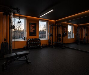 A gym with weightlifting equipment, a bench, and a motivational poster.